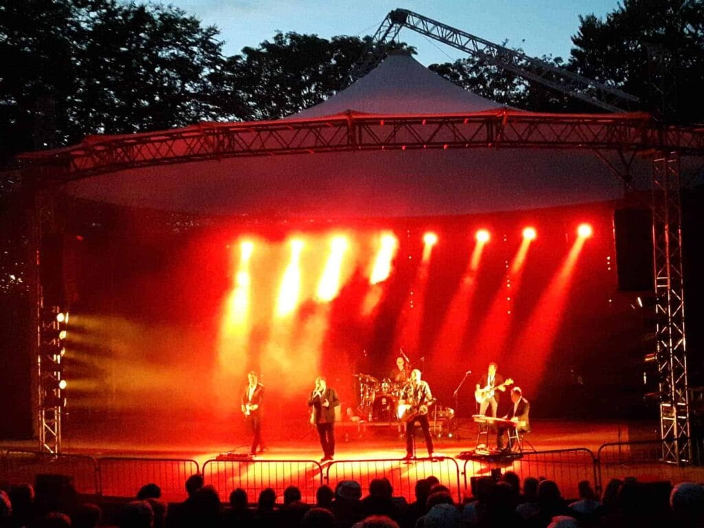 Live koncert på udendørs scene med røde lys.