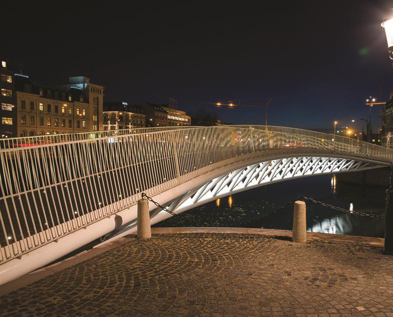 Oplyst fodgængerbro over vand om natten