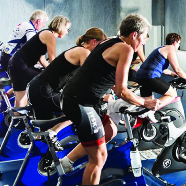 Folk træner på motionscykler i fitnesscenter