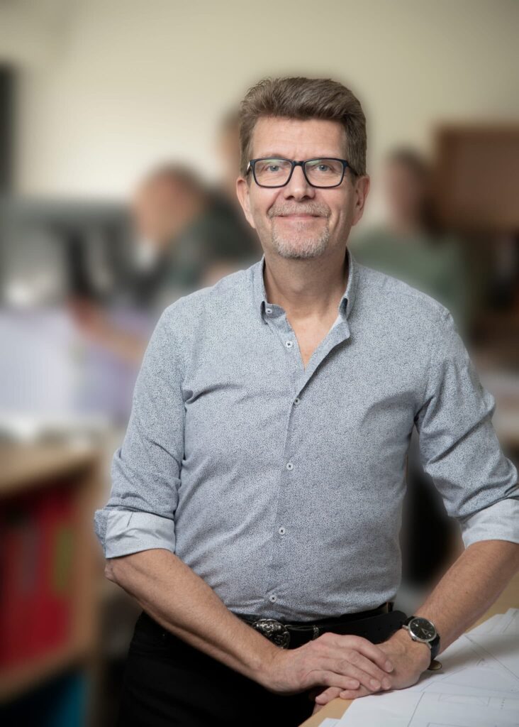 Mand smilende på kontor med papirer på bordet