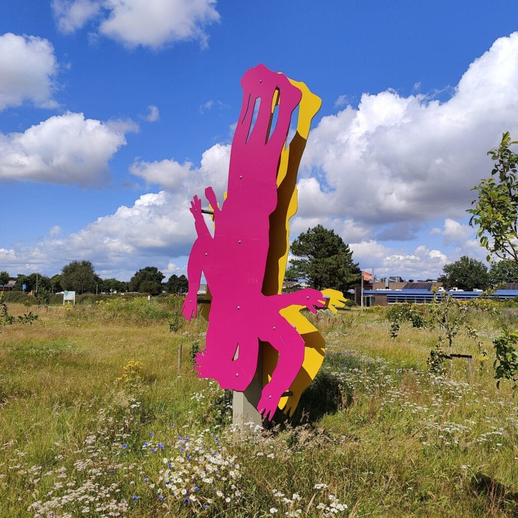 Farverig pink skulptur i blomstrende mark under blå himmel