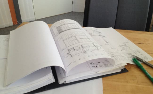 Arkitekttegninger og noter på skrivebord
