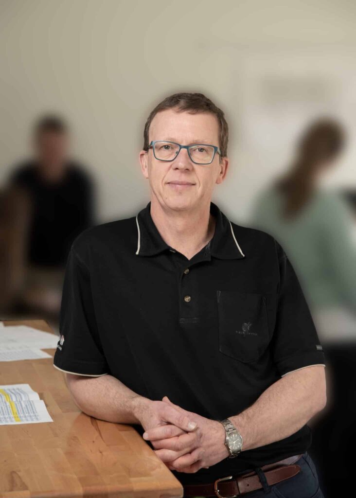 Mand med briller står ved et bord