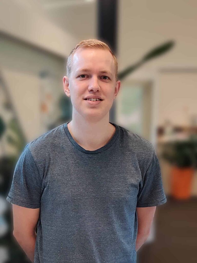 Ung mand i grå t-shirt smiler indendørs