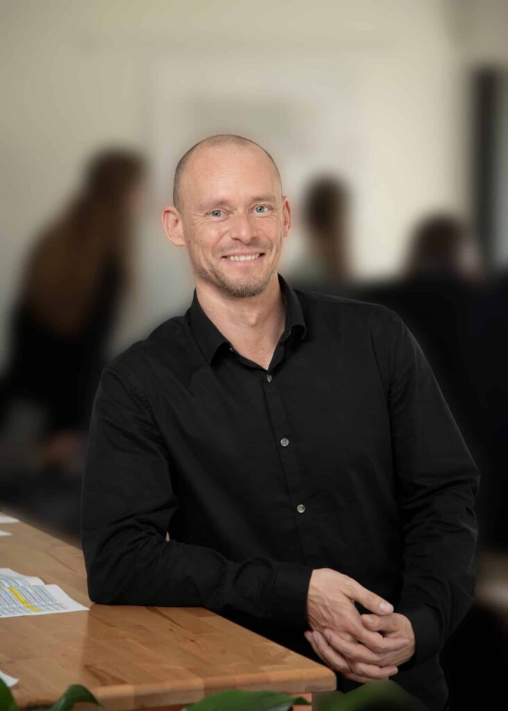 Mand i sort skjorte smiler på kontor
